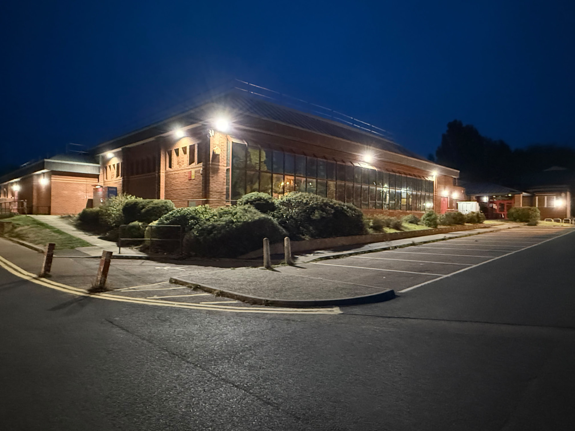 external LED wall lighting on a leisure centre at night, glazed frontage and car park